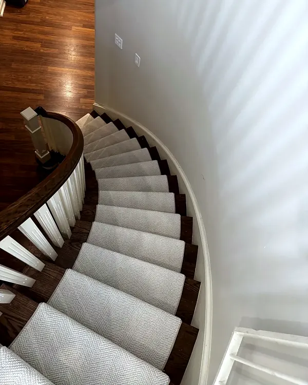Curved staircase from above, carpeted treads with dark wood stringer and white balusters