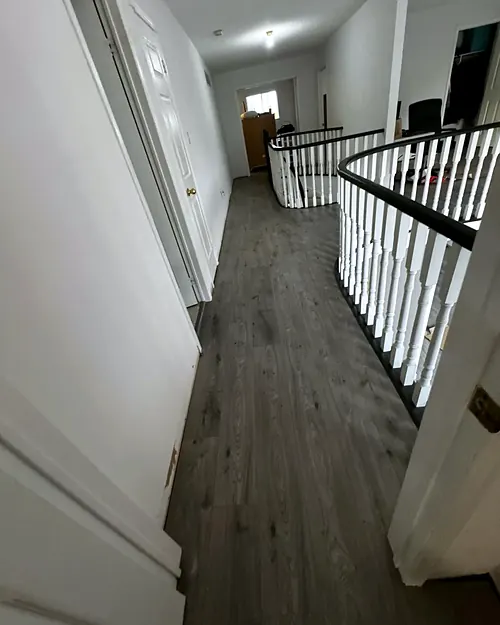 Grey plank floor along an open upstairs landing with a black railing