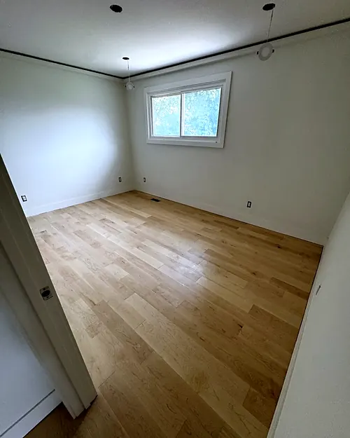 Light oak plank floor in an empty bedroom with a window