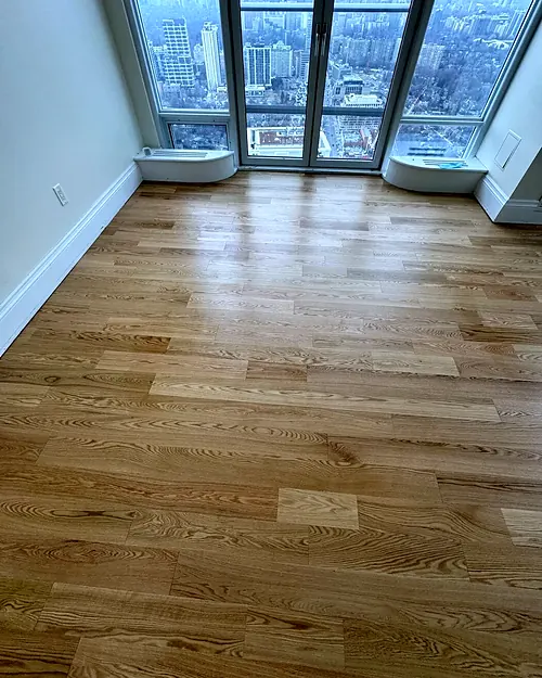 White oak plank floor in a high-rise condo, floor-to-ceiling windows overlooking Toronto